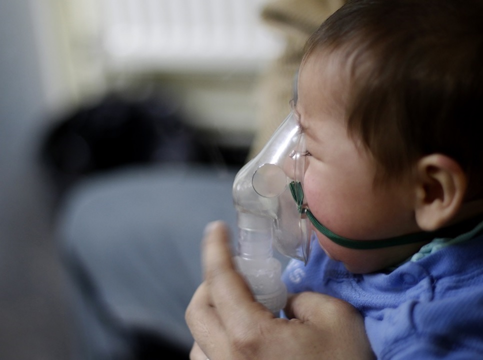 An infant breathing oxygen from a mask
